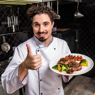 Chef de cozinha mostrando um prato com um belo bife ancho harmonizado com vegetais italianos