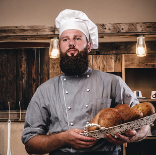 Chef de cozinha especialista em massas artesanais mostrando uma cesta com pães fresqueinhos